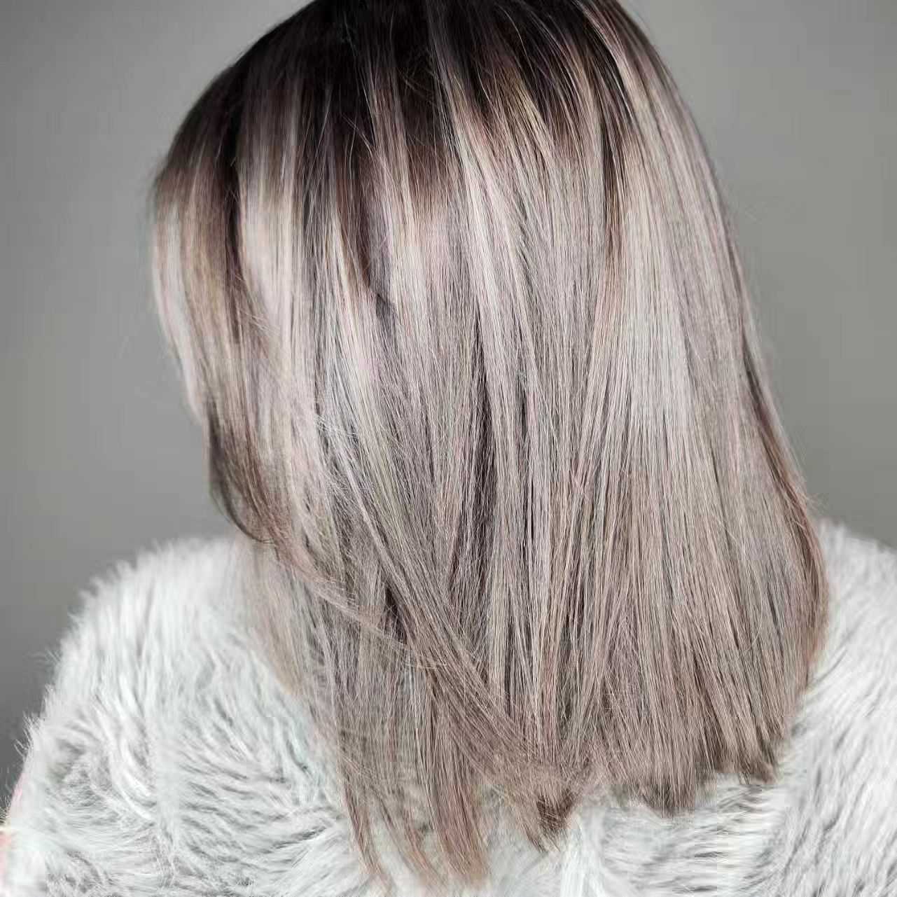 Close-up of a person with straight, shoulder-length, ice blonde hair with dark roots.